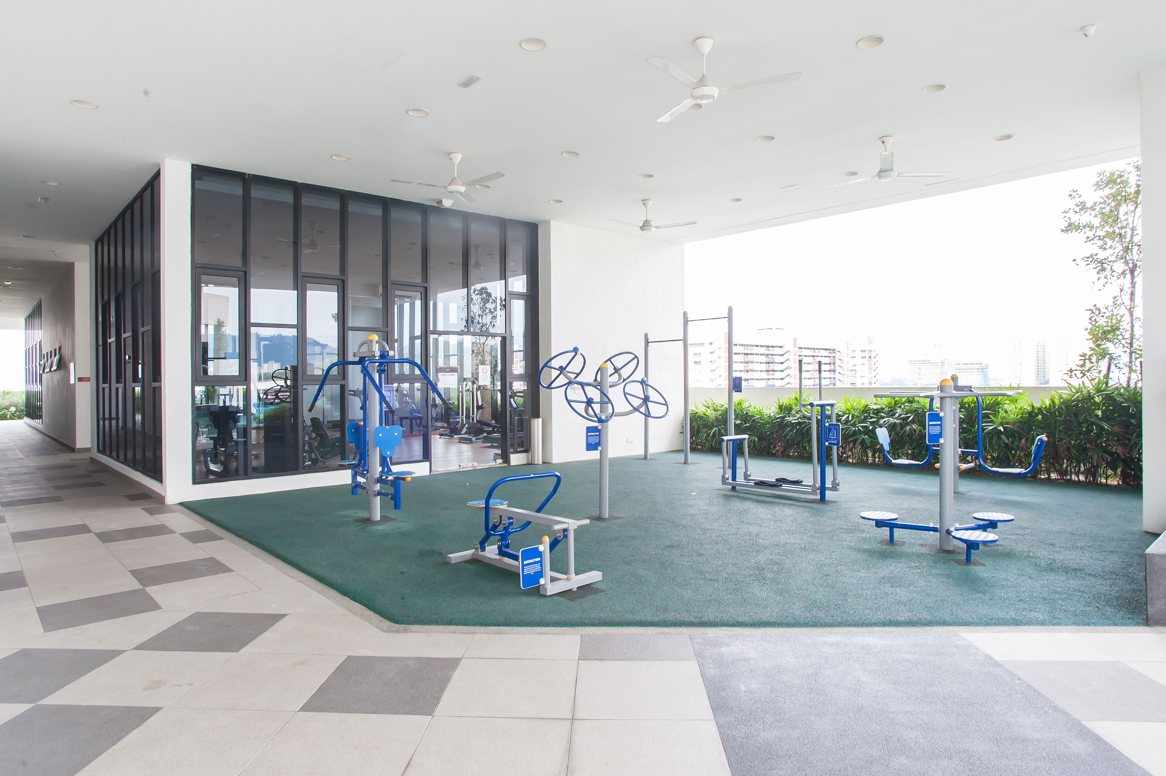 A modern gym with exercise equipment, large windows, and a view of the city.