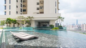 A modern building with a swimming pool, a lounge chair, and a cityscape in the background. - J Dupion Residences at Kuala Lumpur KLCC (Kuala Lumpur)