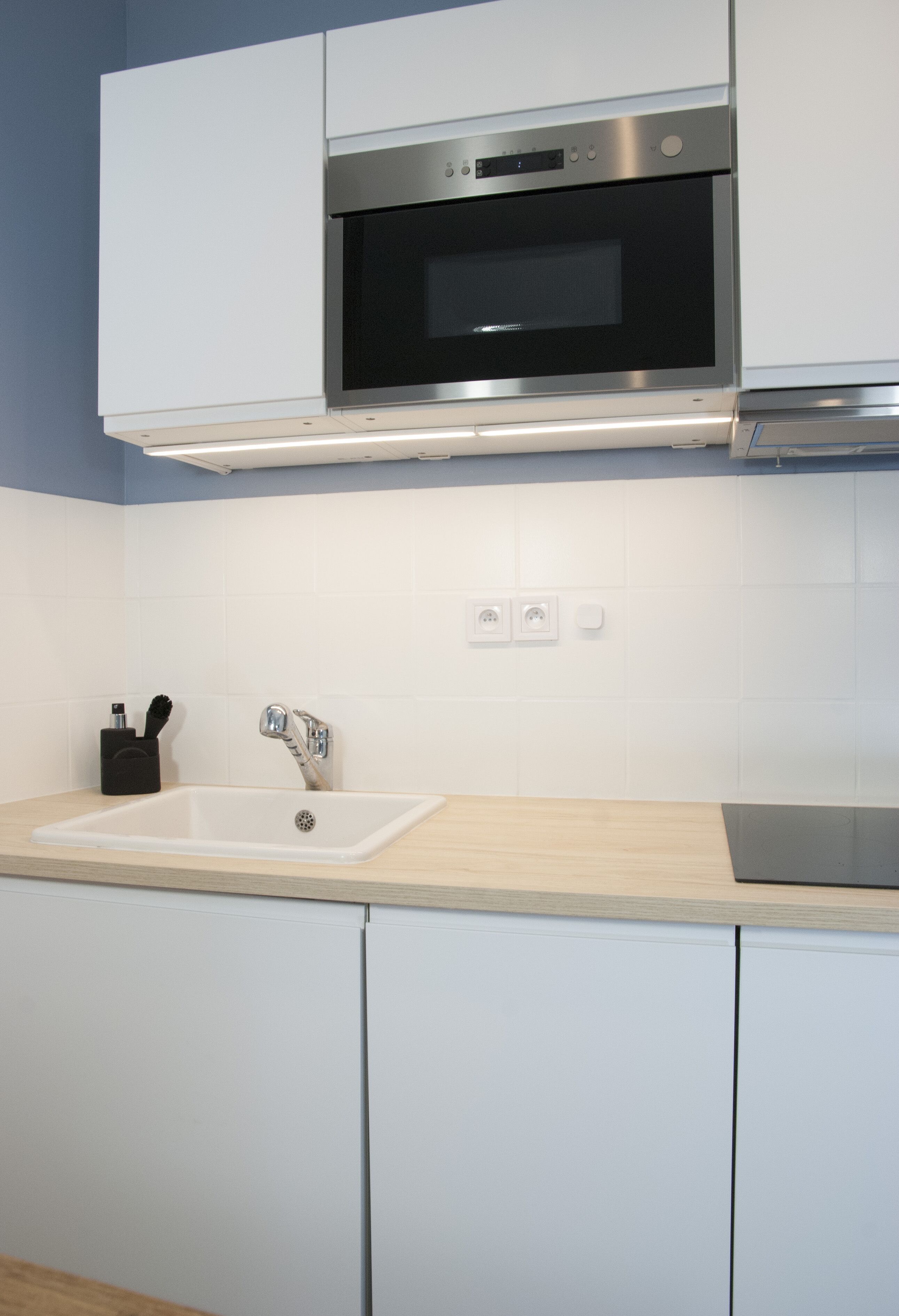 Una cocina moderna con armarios blancos, horno de acero inoxidable, un lavamanos y una encimera.
