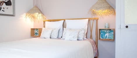 Un dormitorio con una cama, dos mesitas de noche, una puerta y adornos en la pared.