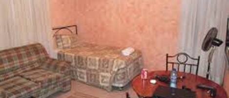 A small, cozy room with a plaid sofa, a small table, and a chair.