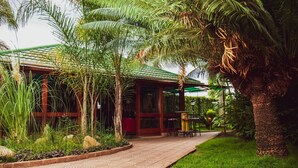 A building with a green roof, surrounded by lush greenery and a paved walkway. - Chabanga Lodge (Ndola)