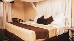 A hotel room with a bed, a bedside table, a chair, and a curtain. - Chabanga Lodge (Ndola)