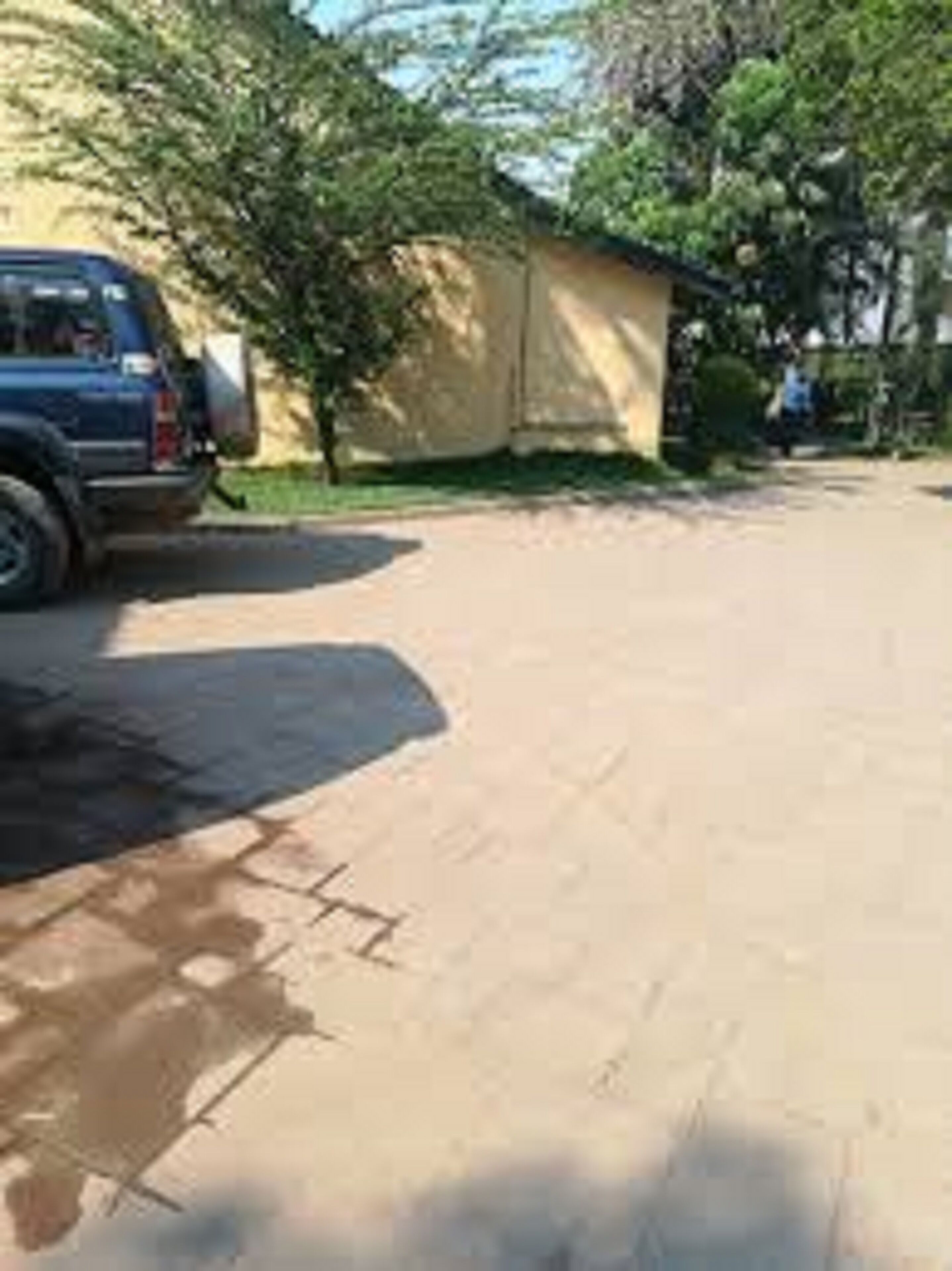 Egy parkoló, ahol egy kék színű terepjáró parkol egy épület közelében.