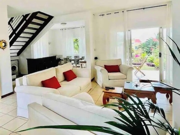 A living room with a sofa, armchair, and a coffee table. There is a staircase leading to another room.
