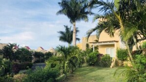 Un hôtel doté d’un jardin bien entretenu, de palmiers et offrant une vue sur un ciel dégagé.