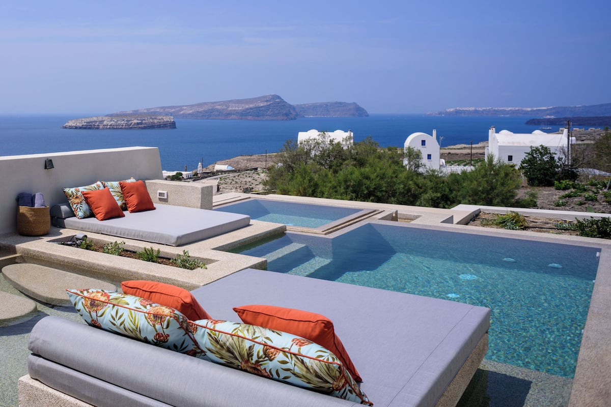 A rooftop pool area with lounge chairs and a view of the sea and distant islands.