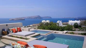 A rooftop pool area with lounge chairs and a view of the sea and distant islands.