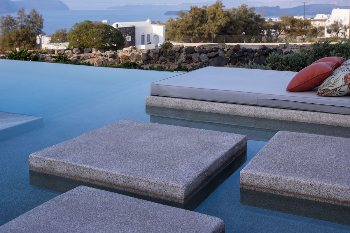 A pool area with stone steps and a view of a coastal landscape.