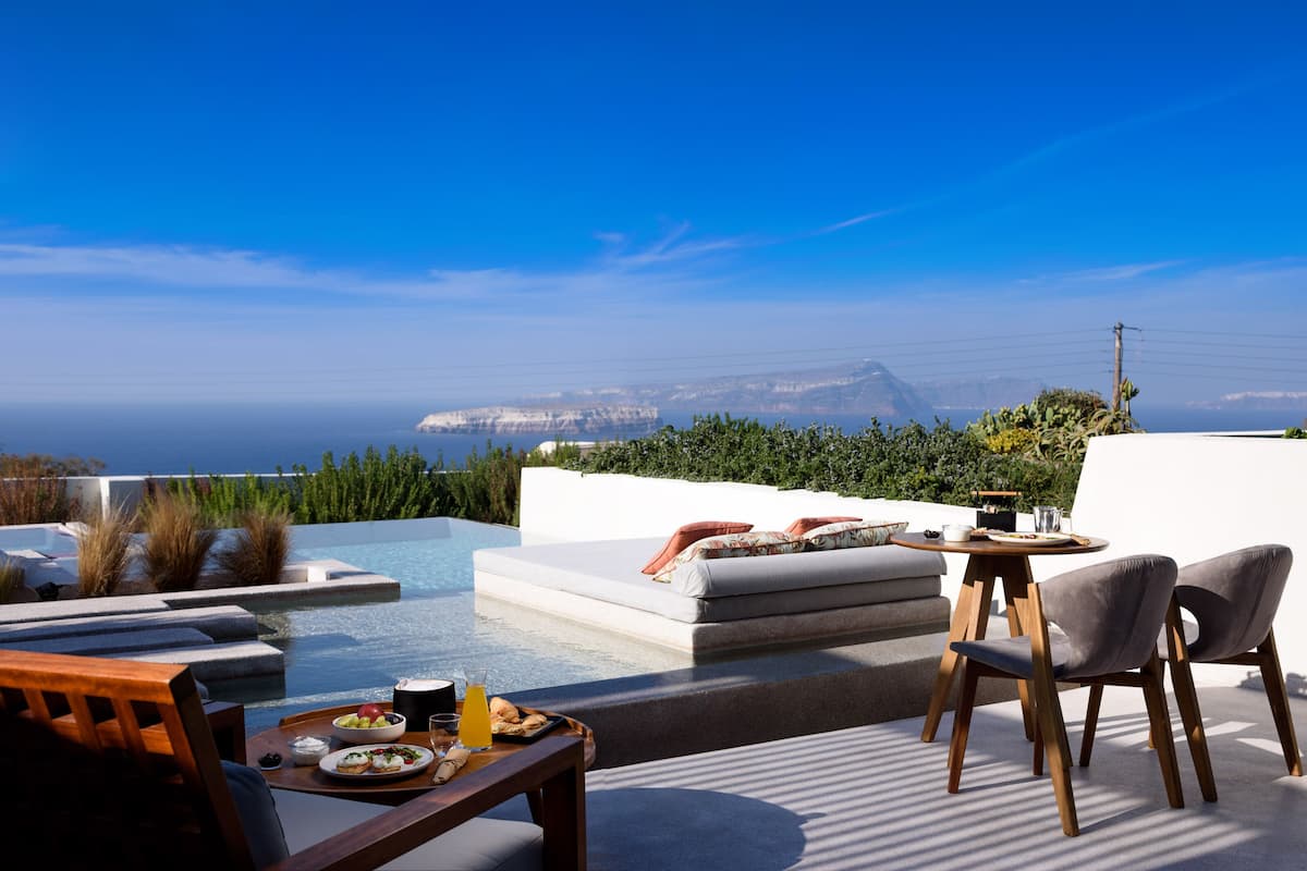 A rooftop terrace with a pool, seating area, and dining setup overlooking a mountainous landscape.