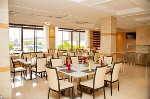 Un comedor amplio con varias mesas y sillas, ventanas grandes y un diseño de interiores moderno.
