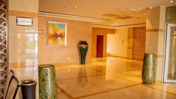 A hotel lobby with a polished floor, a painting on the wall, and two decorative vases.