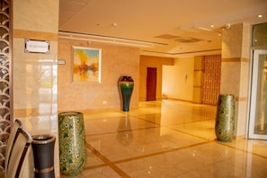 A hotel lobby with a polished floor, a painting on the wall, and two decorative vases. - Hotel Africana (Lusaka)