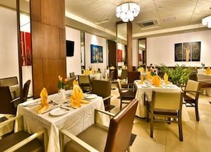 A restaurant with tables set for dining, featuring a chandelier and artwork on the walls. - Hotel Africana (Lusaka)