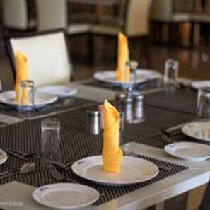 Una mesa de comedor dispuesta con platos, cubiertos y servilletas.