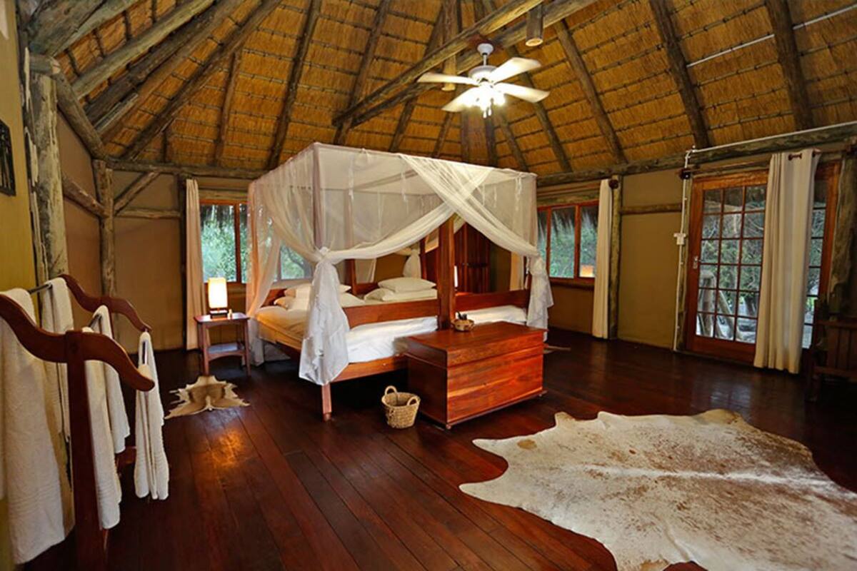 A room with a wooden bed, a canopy bed, a wooden chest, and a large fur rug.