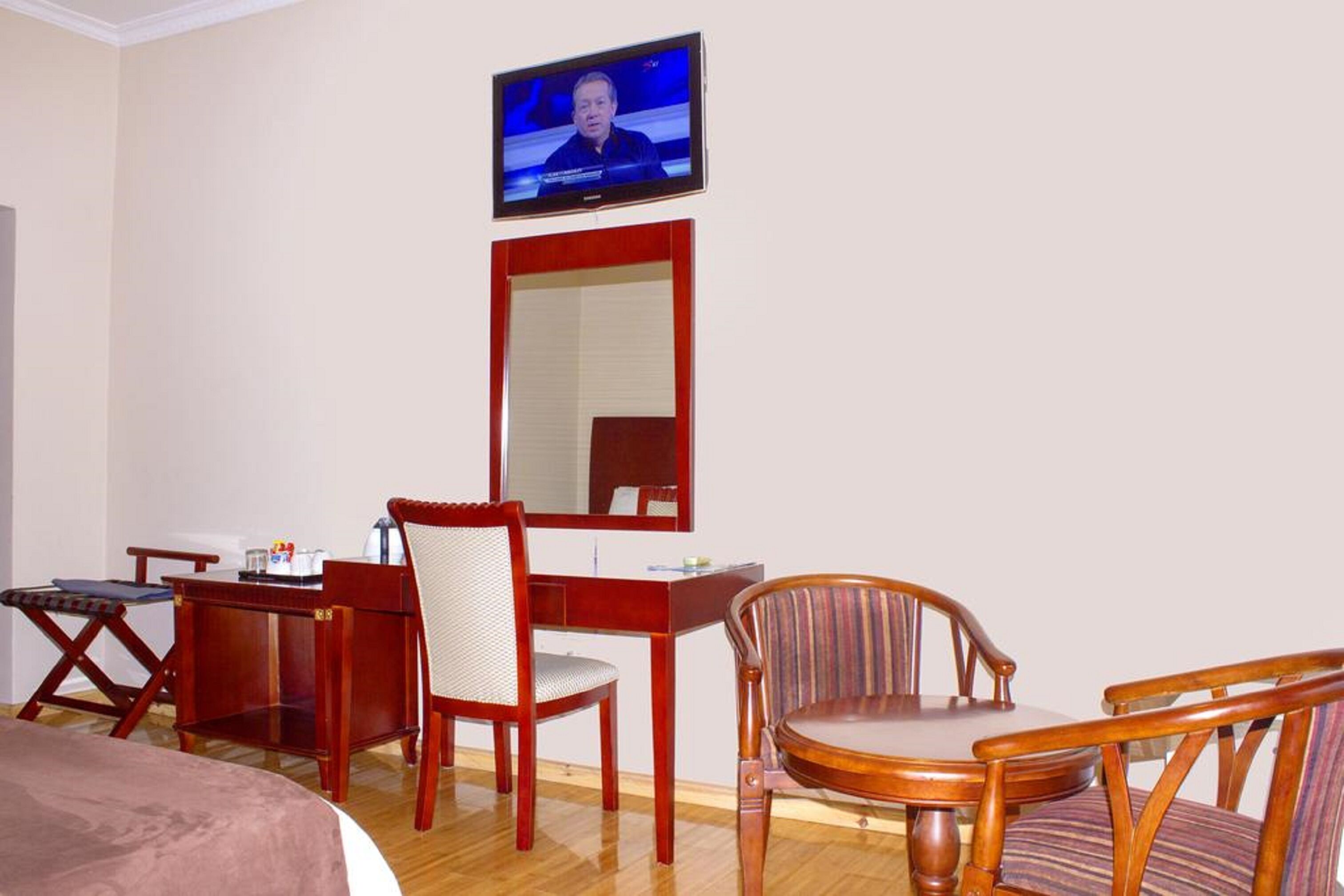 Une chambre d’hôtel comprenant un lit, un bureau avec une chaise, un téléviseur fixé au mur et un miroir.
