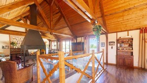 A spacious room with a high wooden ceiling, a fireplace, and a large window. - Quaint Holiday Home in Ferce (Ferce)