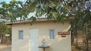 Un piccolo edificio con la scritta "SENSATIONS SPA", con una fontana antistante, circondato da alberi.