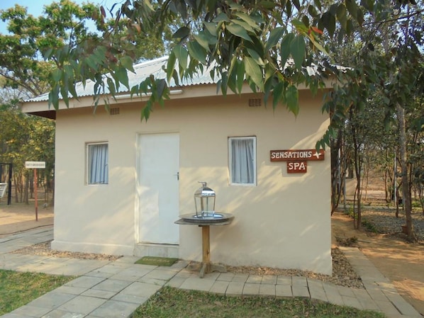A small building labeled "SENSATIONS SPA" with a water fountain in front, surrounded by trees.