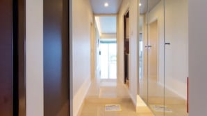 A modern hotel corridor with glass doors, a tiled floor, and a view into a room with a large window. - Longvacation Okinawa 103 (Onna)