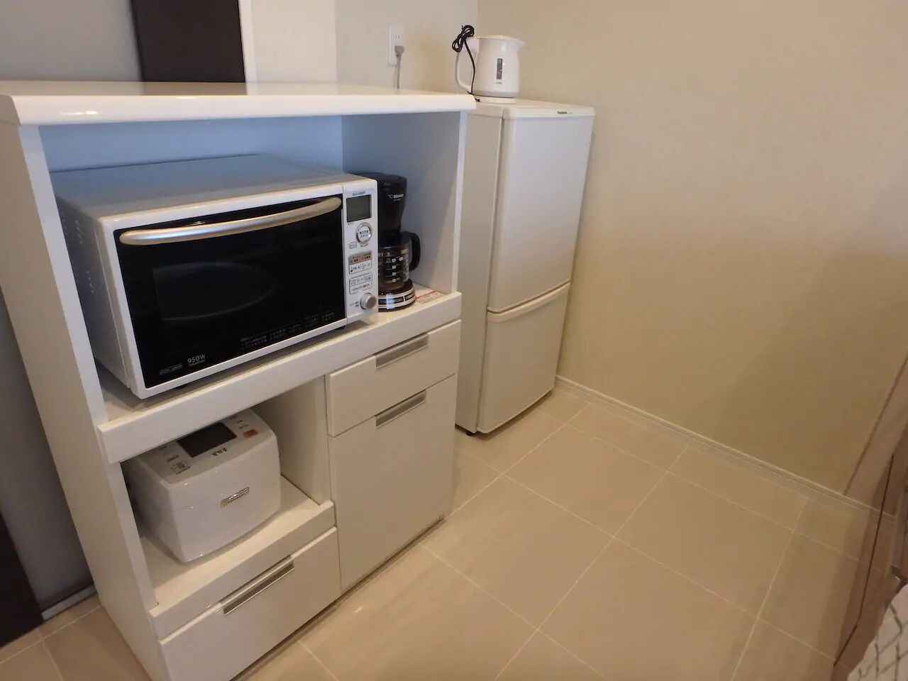 Una cocina compacta equipada con microondas, cafetera y refrigerador pequeño.