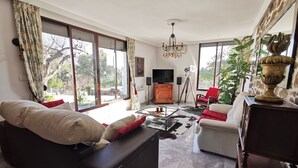 A living room with a sofa, a coffee table, a TV, and a large window. - C. R. El Mirador de Acebo**** 4/10 pax, swimming pool, SPA, garden, N° TR-CC-00339 (Acebo-Càceres)