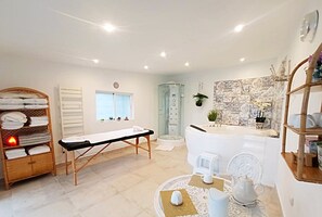 Bathroom features a central bathtub, glass-enclosed shower, and wooden bench.