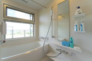 Bathroom features a large bathtub, shower area, and window with an outdoor view.