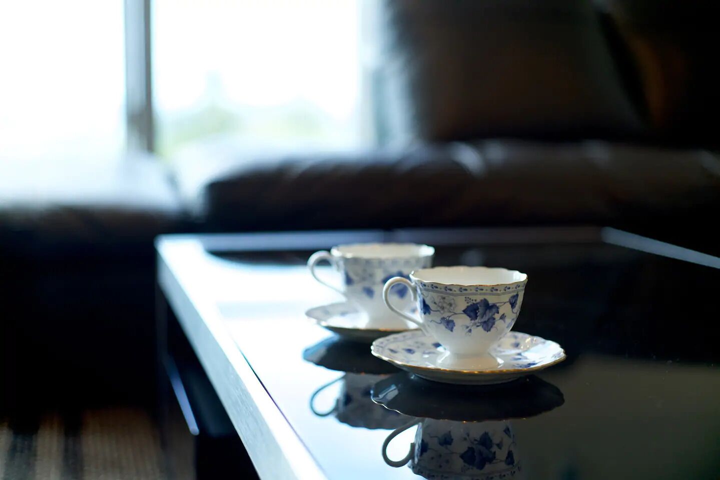 Two white cups with blue floral designs on a reflective surface.