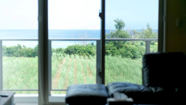 A room with a large window offering a view of the sea and greenery. - Longvacation Okinawa 201 (Onna)