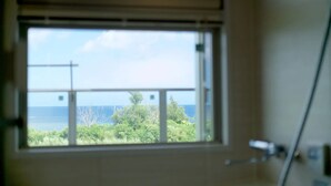 A room with a window overlooking a body of water and greenery. - Longvacation Okinawa 201 (Onna)