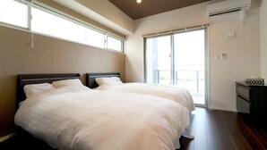A hotel room with two beds, large windows, and an air conditioning unit. - Longvacation Okinawa 201 (Onna)