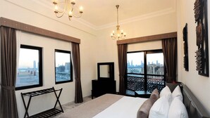 A hotel room with a large bed, a view of the cityscape, a chandelier, and a black dresser. - Marbella Luxury 2 Bedrooms Balcony (Dubai)