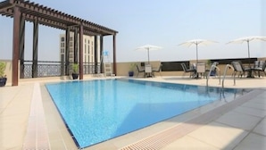 A rooftop swimming pool with a pergola, lounge chairs, and umbrellas. - Marbella Luxury 2 Bedrooms Balcony (Dubai)