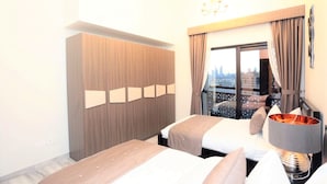 A hotel room with two beds, a wardrobe, a large window with curtains, and a city view. - Marbella Luxury 2 Bedrooms Balcony (Dubai)
