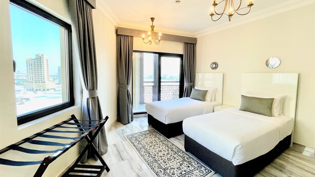 A hotel room with two beds, a large window, a chandelier, and a view of the city. - Marbella Executive 2 Bedrooms Balcony (Dubai)