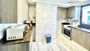 A modern kitchen with a microwave, stove, and sink. - Marbella Executive 2 Bedrooms Balcony (Dubai)
