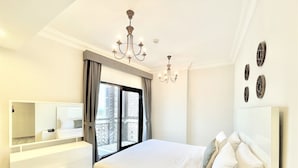 A hotel room with a large bed, a bedside table, a mirror, and a window with curtains. - Marbella Executive 2 Bedrooms Balcony (Dubai)