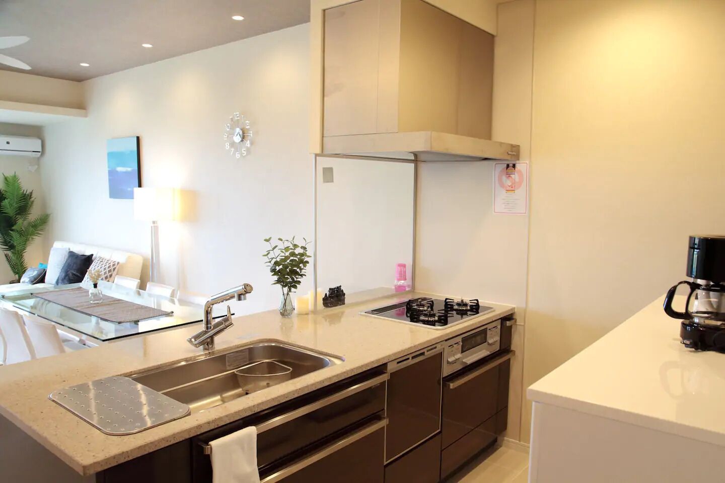 A modern kitchen with a gas stove, sink, and a coffee maker.