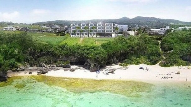 A coastal resort with a beachfront, a multi-story building, and lush greenery. - Longvacation Okinawa 206 (Onna)
