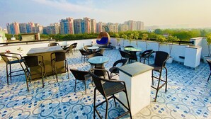 Una terraza en la azotea con mesas al aire libre, una zona de bar y vistas a rascacielos.