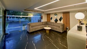 Un vestíbulo moderno con un sofá modular, una mesa redonda de centro y un mostrador de recepción.