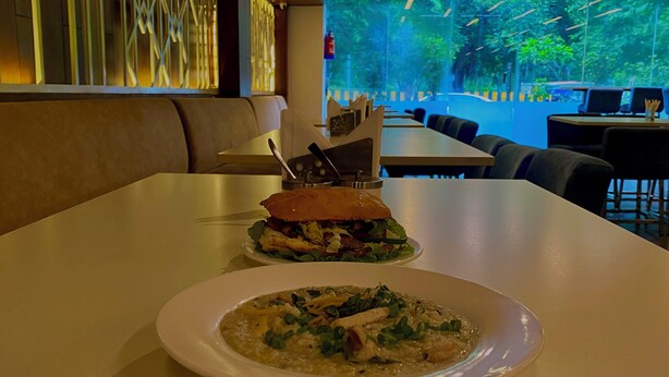 Un restaurante con una mesa dispuesta para dos personas, que incluye un sándwich y un tazón de sopa.
