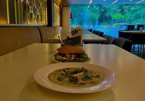 A restaurant setting with a table set for two, featuring a sandwich and a bowl of soup. - Ace Iconic (Greater Noida)