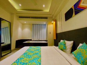 A hotel room with a bed, a desk, a mirror, and a window with curtains. - Ace Iconic (Greater Noida)
