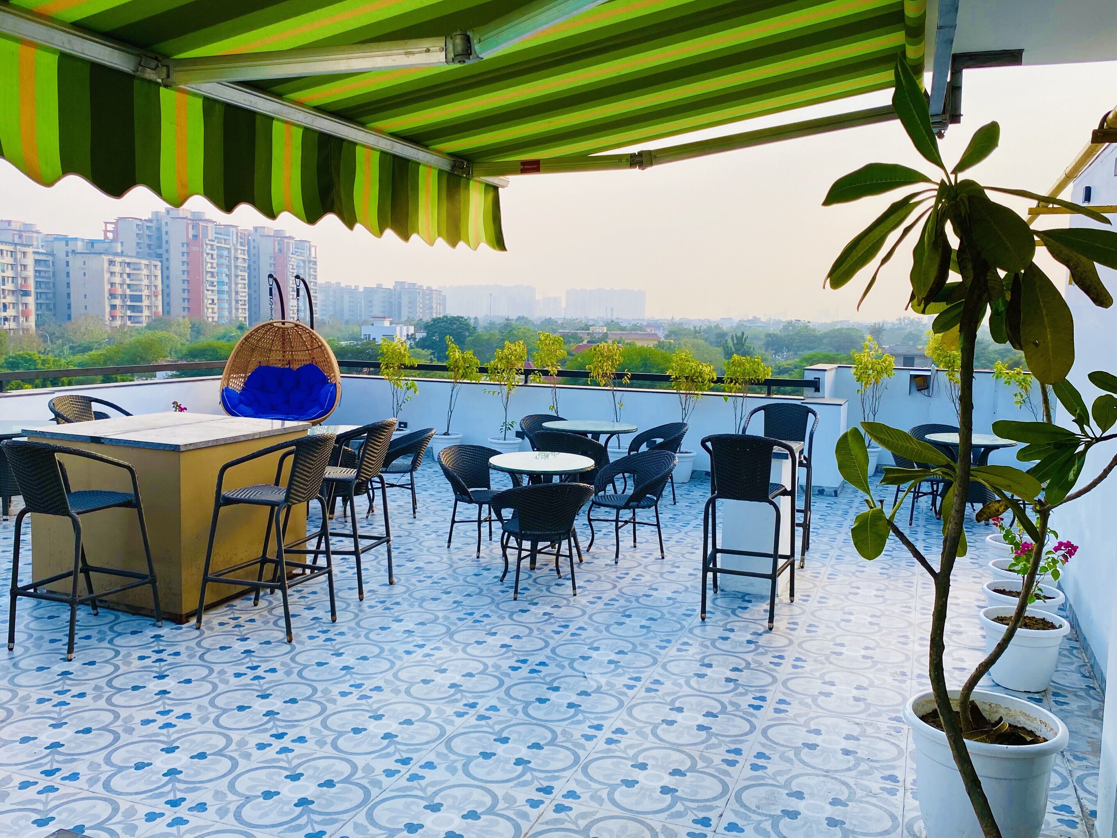 Una terraza en la azotea con suelo estampado, mobiliario exterior, zona de bar y plantas en macetas.