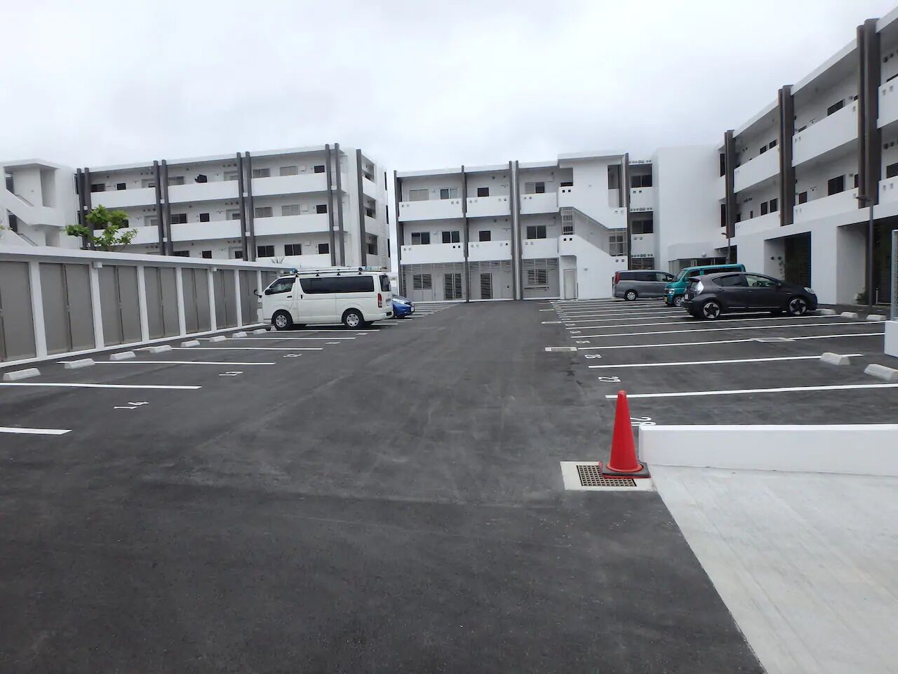 A parking lot with multiple cars and a building in the background.