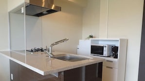 A modern kitchen with a stainless steel range hood, a built-in sink, and a microwave. - Longvacation Okinawa 209 (Onna)