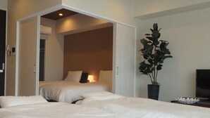 A hotel room with two beds, a potted plant, a TV, and a bedside table. - Longvacation Okinawa 209 (Onna)